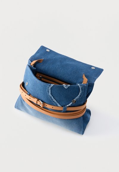 Μπλε τζιν τσαντάκι χειρός με λουρί ζώνης από δέρμα ταμπά και καρδιά με φθαρμένη λεπτομέρεια στην μπροστινή τσέπη, ανοιχτό με ορατό φερμουάρ στο εσωτερικό.