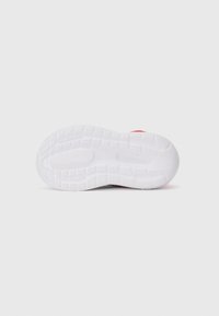 Semelle de sneaker rouge vue par le dessous, avec une semelle texturée blanche et un logo "Cloudfoam" visible sur un fond blanc uni.