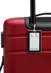 Rood harde koffer met een gestructureerde oppervlakte, uitschuifbare zwarte handgreep en een duidelijk ID-label met contactgegevens.