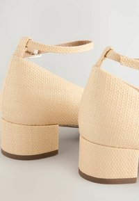 Beige Blockabsatzschuhe mit gewebter Textur, Knöchelriemen und glattem Design. Flacher, stabiler Absatz für Stabilität. Minimalistischer Stil.