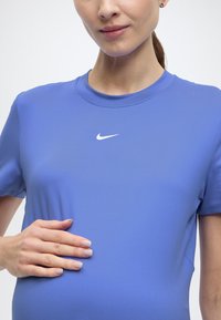 Μπλε αθλητική μπλούζα Nike με κοντά μανίκια, λαιμόκοψη στρογγυλή και λευκό λογότυπο swoosh στο στήθος, κατασκευασμένη από λείο, ελαστικό ύφασμα.