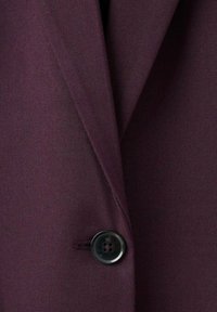 Blazer burdeos oscuro con tejido suave, solapa con muesca y un solo botón negro en la parte delantera.