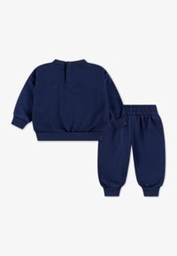 Marineblå genser og bukse i sett laget av mykt stoff. Genseren har rund hals og ribbestrikkede mansjetter, mens buksene har elastisk midjebånd.