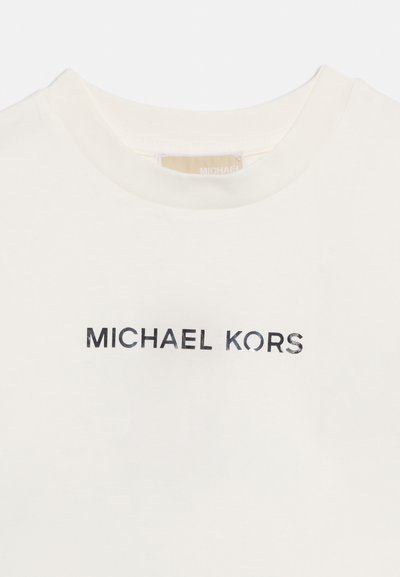 Λευκό μπλουζάκι με στρογγυλή λαιμόκοψη και την επιγραφή «MICHAEL KORS» σε μαύρα κεφαλαία γράμματα στο κέντρο του στήθους.