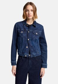 Granatowa denimowa kurtka o klasycznym designie, z dwoma przednimi kieszeniami, zapięciami na mosiężne guziki i detalami szwów. Gładka tekstura.
