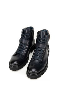 Botas de tobillo de cuero azul oscuro con una textura lisa, cordones en la parte delantera, cremallera lateral, detalle de hebilla y suela de goma negra gruesa.