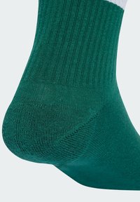Vihreä puuvillapäärme, jossa on kantalaput ja ribbitekstuuri. Materiaali on sileä ja hieman kiiltävä, ja se kontrastoi valkoisen muodikkaan päärmeen kanssa.