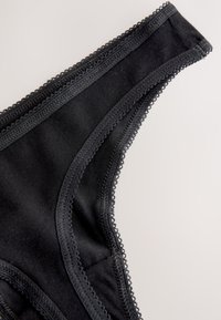 Perizoma nero in morbido cotone, con delicato bordo in pizzo lungo i bordi e una texture liscia con un design minimalista.