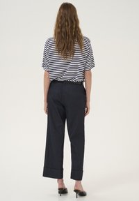 Paskowane, oversize'owe t-shirt z krótkimi rękawami w połączeniu z ciemnoniebieskimi, szerokimi spodniami dżinsowymi z podwiniętym dołem i tylnymi kieszeniami.