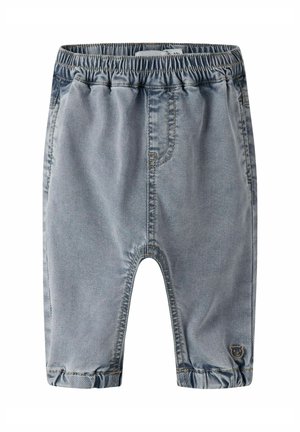 Jean pour tout-petit à taille élastique bleu clair avec ourlets retroussés et petite écusson d'ours près de la cheville gauche.