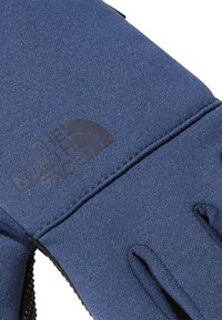Marineblaue Handschuh aus strukturiertem Stoff, mit einem Logodruck und verstellbarem Handgelenkband. Verstärkte Fingerspitzenakzente für Langlebigkeit.