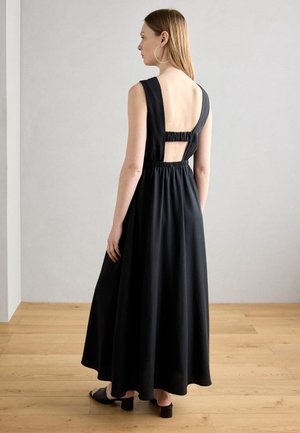Robe maxi noire avec un corsage ajusté, de larges bretelles et un dos élastique. Présente une découpe en forme de trou de serrure et une jupe fluide. Texture de tissu lisse.
