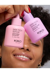 Se muestran dos botellas de serum de KIKO Milano: una rosa etiquetada como "Sérum Calmante", y la otra lila etiquetada como "Sérum Elixir de Juventud".