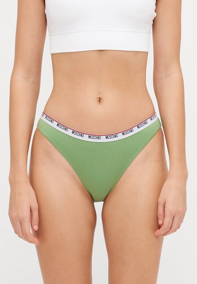 Žalias medvilninis bikini apatinis trikotažas su plonu, baltu elastiniu juosmeniu, kuriame yra juodas logotipas. Dizainas yra paprastas ir prigludęs.
