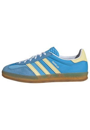 Niebieski but sportowy Adidas Gazelle z kremowymi paskami, gumową podeszwą, białymi sznurówkami i kremową zakładką na pięcie, pokazany z profilu bocznego, skierowany w prawo.