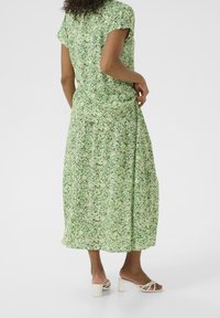 Maxi-jurk in groene bloemenprint met korte mouwen, een relaxte pasvorm en zachte stof. Kenmerkt zich door een vloeiende uitstraling en een lichte, ademende textuur.