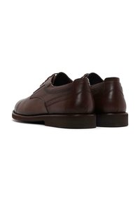 Zapatos de cuero marrón con una textura suave, punta redonda y detalles de cordones. Presenta acentos perforados a lo largo de los lados y una suela resistente.