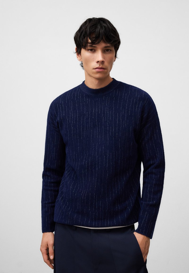 Maglione a maglia blu navy con strisce verticali testurizzate, colletto rotondo e maniche lunghe, realizzato in un materiale morbido e caldo.