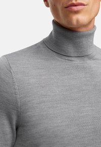 Grauer Rollkragenpullover mit gerippter Struktur und tailliertem Design, hoher Kragen und nahtlosen Schultern.