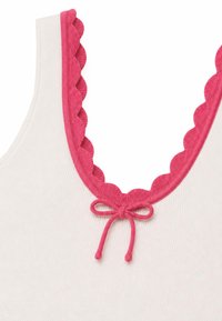 Haut en tissu côtelé blanc avec une bordure rose festonnée autour du col et un petit nœud noué au centre devant.