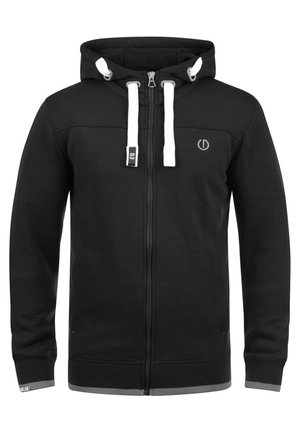 Crna zip-up dukserica od pamuka s dodatkom elastina, s prednjim zatvaračem, ušicama za stezanje i bijelim detaljima na kapuljači i rukavima. Jednostavan dizajn.