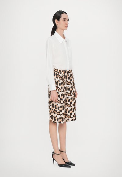 White long-sleeve shirt with a collar paired with a knee-length leopard print skirt. Black pointed-toe heels complete the outfit.