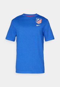 Blå Nike T-shirt med korte ærmer, rund halsudskæring og Atletico Madrid-logo på venstre bryst. Blødt stof med en glat tekstur.