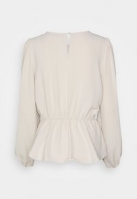 Cream peplum blouse with long sleeves, gathered cuffs, and a keyhole back. Made from lightweight, textured fabric.
