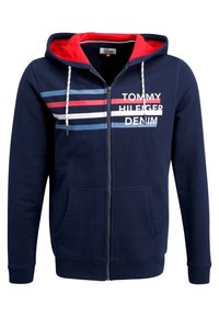 Marinfärgad zip-up hoodie med röda detaljer inuti huvan, prydd med vita och ljusblå ränder samt "TOMMY HILFIGER DENIM"-logotyp på bröstet.