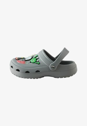 Sabot en caoutchouc gris avec bride de talon ajustable et breloques colorées de personnages de dessins animés sur le dessus, comprenant un extraterrestre vert et un nuage.