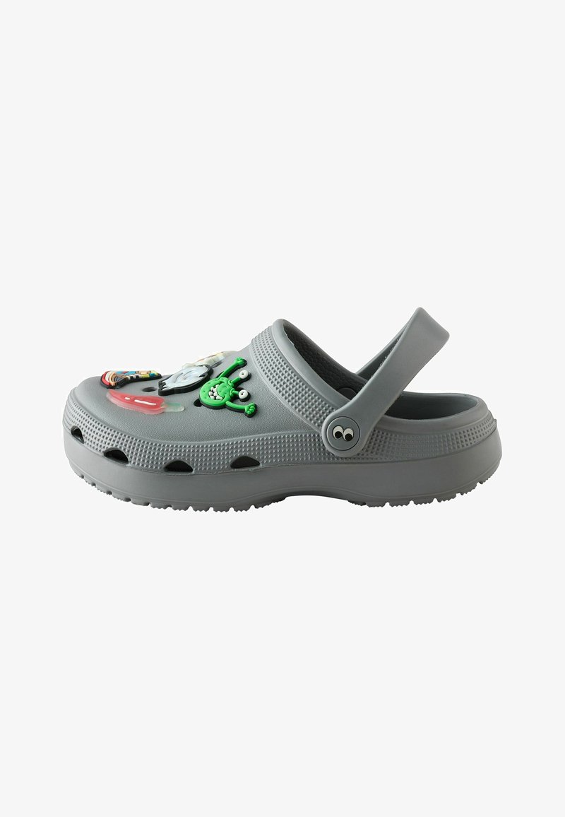 Sabot en caoutchouc gris avec bride de talon ajustable et breloques colorées de personnages de dessins animés sur le dessus, comprenant un extraterrestre vert et un nuage.