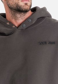 Mörkgrå hoodie med en mjuk textur, featuring en stor huva, tryckknappar och broderad "Sixth June"-logotyp på framsidan.