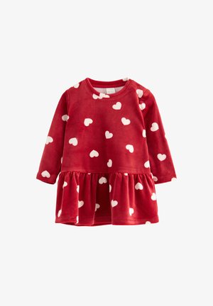 Punainen pitkähiha dressi pehmeästä materiaalista, jossa on valkoisia sydänkuvioita. Siinä on kerrottu hame ja pyöreä kaula-aukko. Sopii rentoon käyttämiseen.
