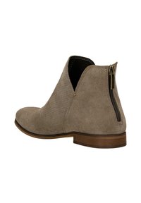 Taupe Wildleder Stiefeletten mit runder Zehenform, offenen Seiten und einem dekorativen Reißverschlussdetail auf der Rückseite. Flache Holzsohle.