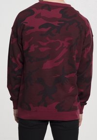 Felpa bordeaux con motivo camouflage nero, maniche lunghe e design a girocollo. Tessuto morbido con una vestibilità comoda.