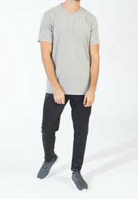 Šedé tričko s krátkým rukávem a texturovaným vzorem je spárováno s černými slim-fit elastickými kalhotami. Celý outfit doplňují šedé sportovní boty.