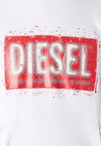 Vit hoodie med en djärv, röd rektangulär logotyp med texten "DIESEL." Trycket har en glansig, vattendrops effekt och struktur.