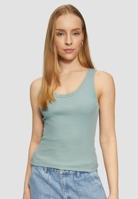 Hellblaues, geripptes Spaghetti-Top mit einem gewellten Spitzenbesatz am Ausschnitt. Der Stoff ist weich und schmal geschnitten, kombiniert mit high-waisted Jeansshorts.