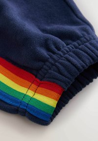 Marineblå sweatpants har en elastisk manchet med flerfarvet stribet mesh-detalje i rød, orange, gul, grøn og blå. Blød tekstur.