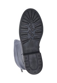 Zwarte rubberen zool met een gestructureerd loopvlak voor grip. Het zijaanzicht toont een grijze stof bovenkant met een lichte glans en subtiele plooien.