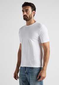 Vit kortärmad T-shirt med rundad nacke, gjord av mjukt tyg, kombinerad med blå denimjeans. Enkelt design, inga synliga mönster eller logotyper.