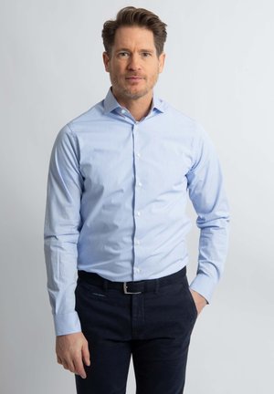 Lichtblauw overhemds met subtiele verticale strepen, lange mouwen, slim fit ontwerp; gecombineerd met donkere marineblauwe broek en zwarte riem.