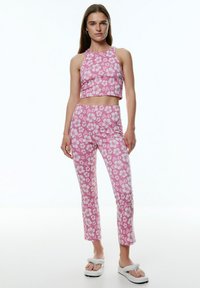 Roze bloemen crop top met bijpassende strakke broeken met een wit bloemenpatroon. De outfit heeft een soepele textuur en een moderne snit.