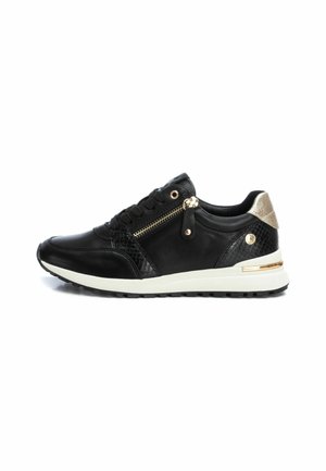 Zapatilla negra de cuero con un panel lateral texturizado, detalles en dorado y un zipper lateral. Presenta una suela intermedia blanca y suela de goma texturizada.