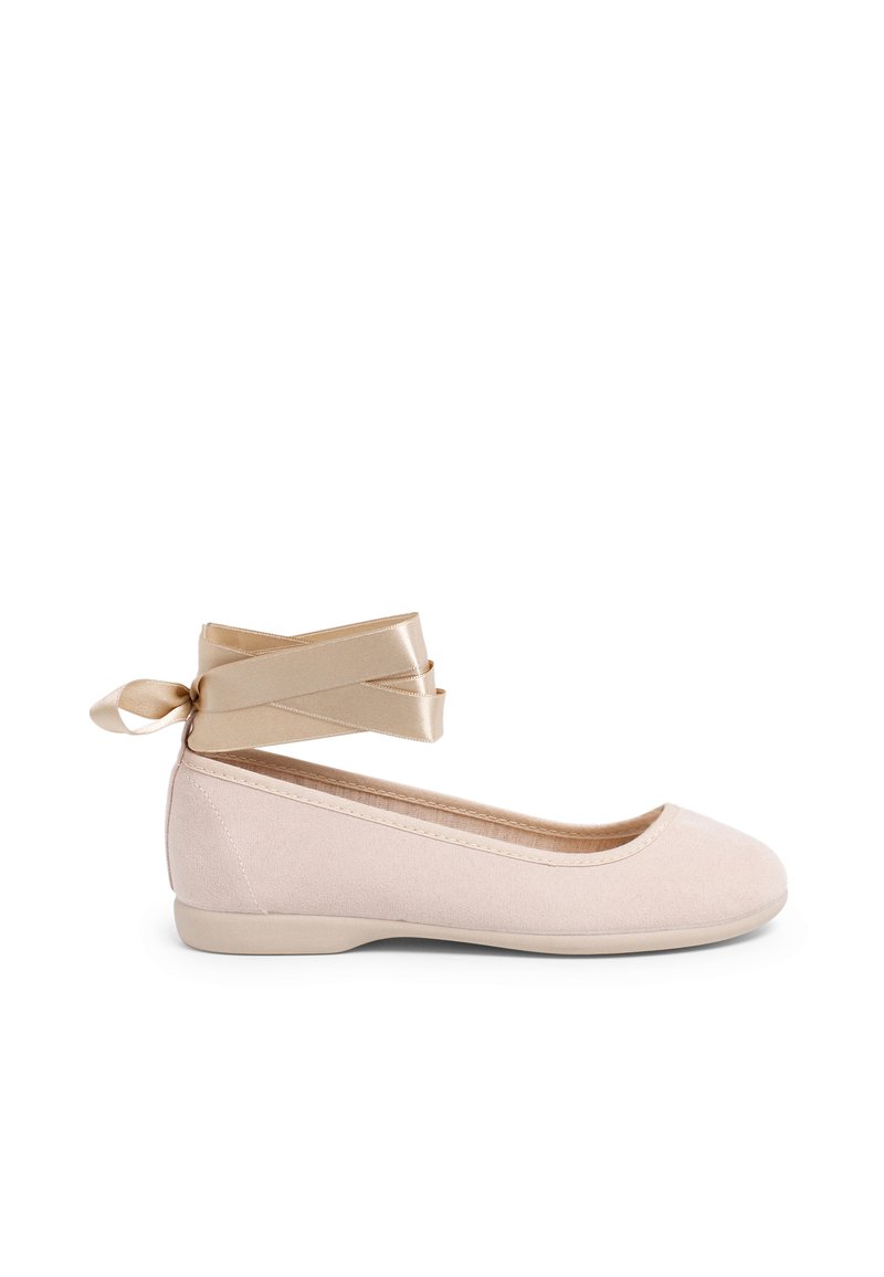 Ballet flats in soft pink fabric with a rounded toe, featuring a satin ankle strap tied in a bow. Flexible sole and smooth texture.