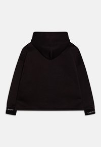 Sudadera negra con capucha redondeada, mangas largas y puños acanalados. Presenta un acento de logo en el puño izquierdo y una textura de algodón suave.