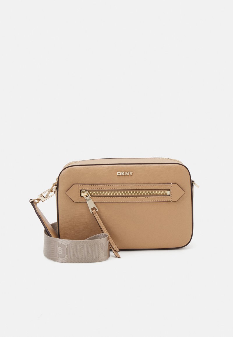 Borsa a tracolla DKNY color crema realizzata in materiale sintetico liscio, con zip dorata, dettagli diagonali e tracolla con logo rimovibile.