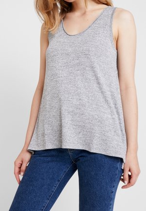 Szary, bezrękawnik z dekoltem w łódkę, wykonany z teksturowanej tkaniny. Luźno opada na talii, zestawiony z ciemnoniebieskimi dżinsami.