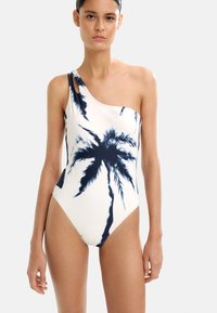 Jedno-boczny strój kąpielowy w kremowej bieli z nadrukiem palm w granatowym kolorze. Gładki materiał, dopasowany krój oraz wycięcie na ramieniu.