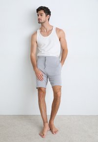 Szare szorty z elastycznym pasem i sznurkiem, w połączeniu z białym topem bez rękawów. Lekki, miękki materiał o dopasowanym kroju.